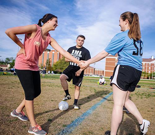 Two girls shake hands before intramural soccer match